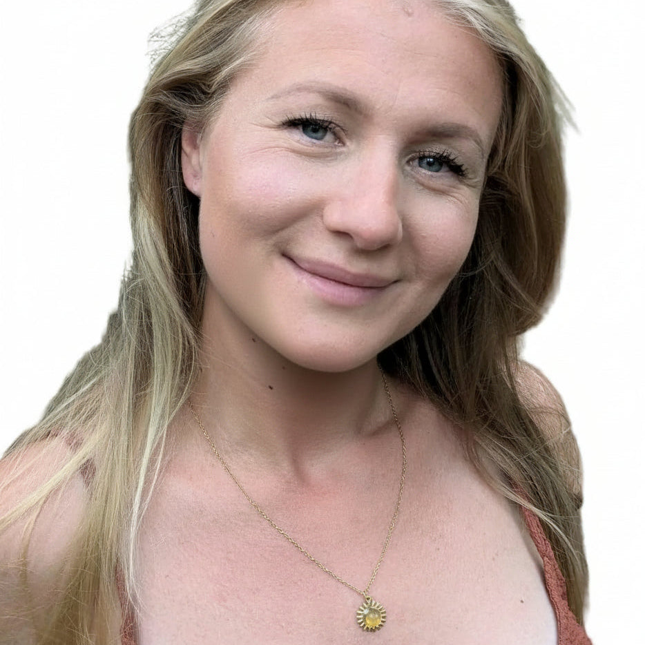 Kvinna bär ett halsband med citrin. Berlocken är formad som en sol med en kristall i mitten.