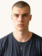 Man bär Nayuga Jewels Nayuga Crystal Cross halsband med svart onyx och guldpläterat kors mot en mörk t-shirt.