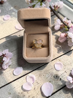 Nayuga Jewels hjärtring i guldpläterat stål med äkta rosenkvarts i en beige sammetsask på marmorunderlag.