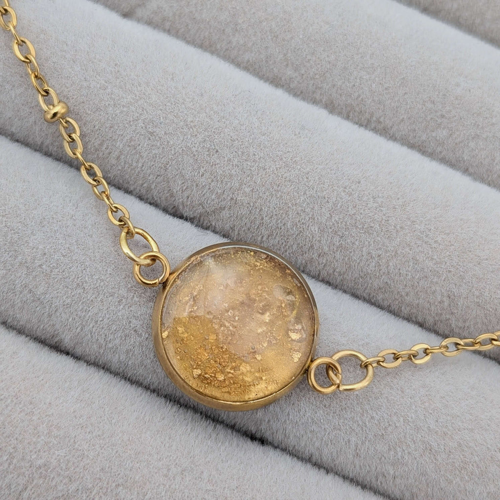 Närbild på ett guld armband med infattade 24K guldflakes från Nayuga Jewels