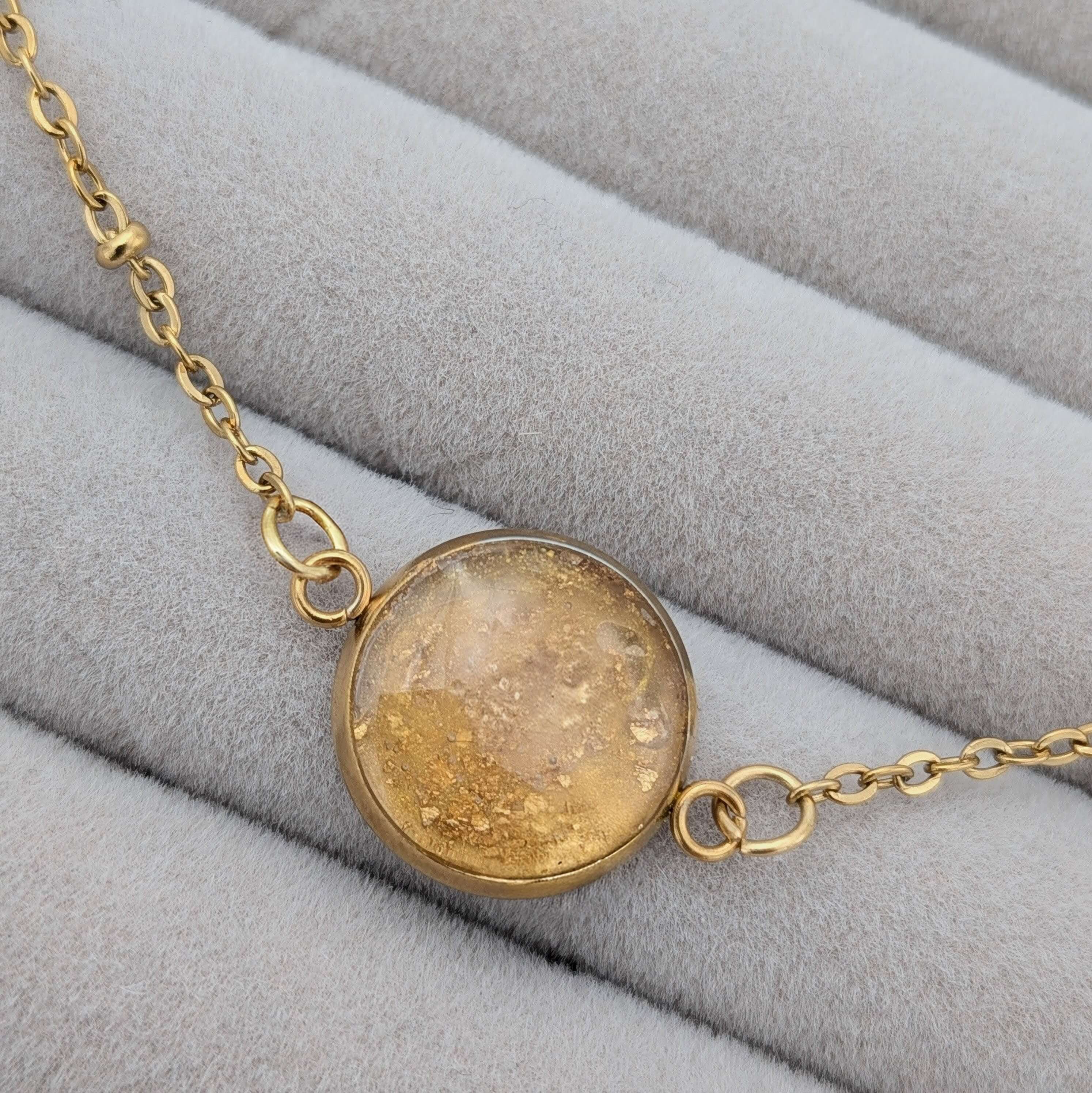 Närbild på ett guld armband med infattade 24K guldflakes från Nayuga Jewels