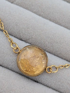 Närbild på ett guld armband med infattade 24K guldflakes från Nayuga Jewels