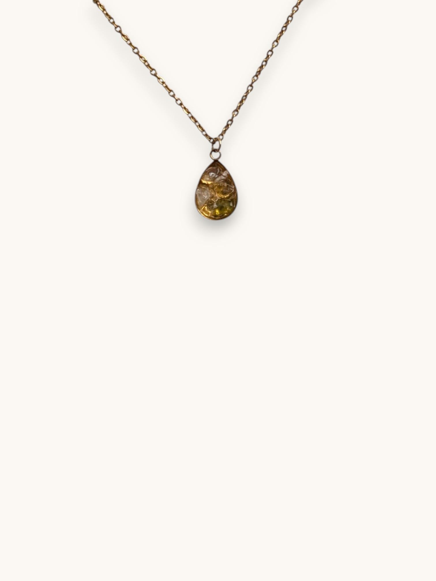 Citrinmagi halsband med droppformad citrin i 14k guldpläterat rostfritt stål på en vit stenplatta