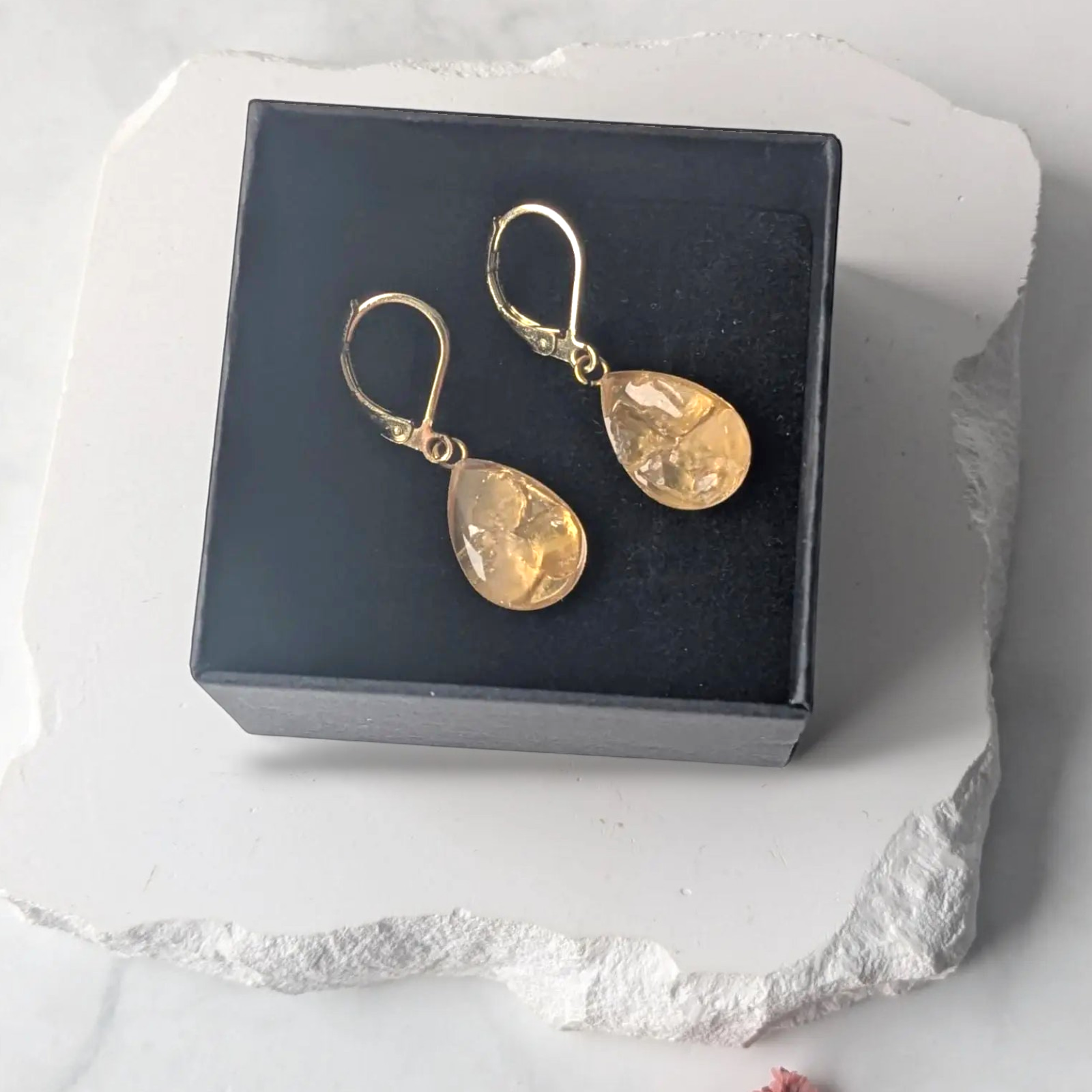 Citrinmagi örhängen med droppformade citrinkristaller i 18K guldpläterat stål, presenterade i en elegant ask.