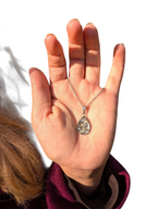 Citrinmagi droppformat halsband med texturerad sten i silverfärgad infattning som hålls i en hand utomhus.