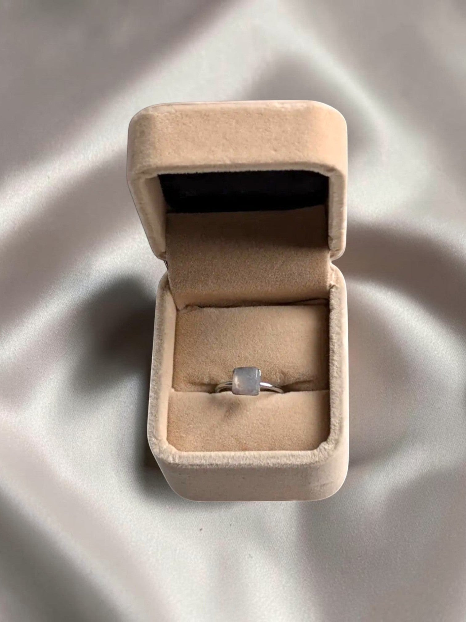 Citrinmagi fyrkantig silverring med äkta månstenskristaller i en elegant beige smyckesask på sidenbakgrund.