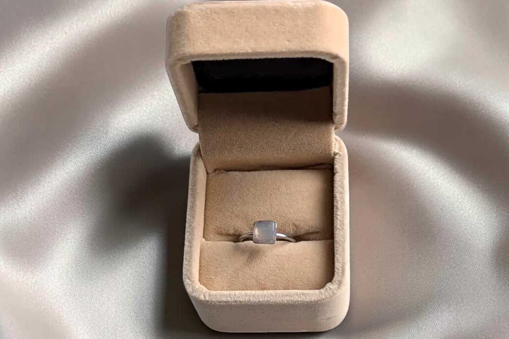Citrinmagi fyrkantig silverring med äkta månstenskristaller i en elegant beige smyckesask på sidenliknande tyg.
