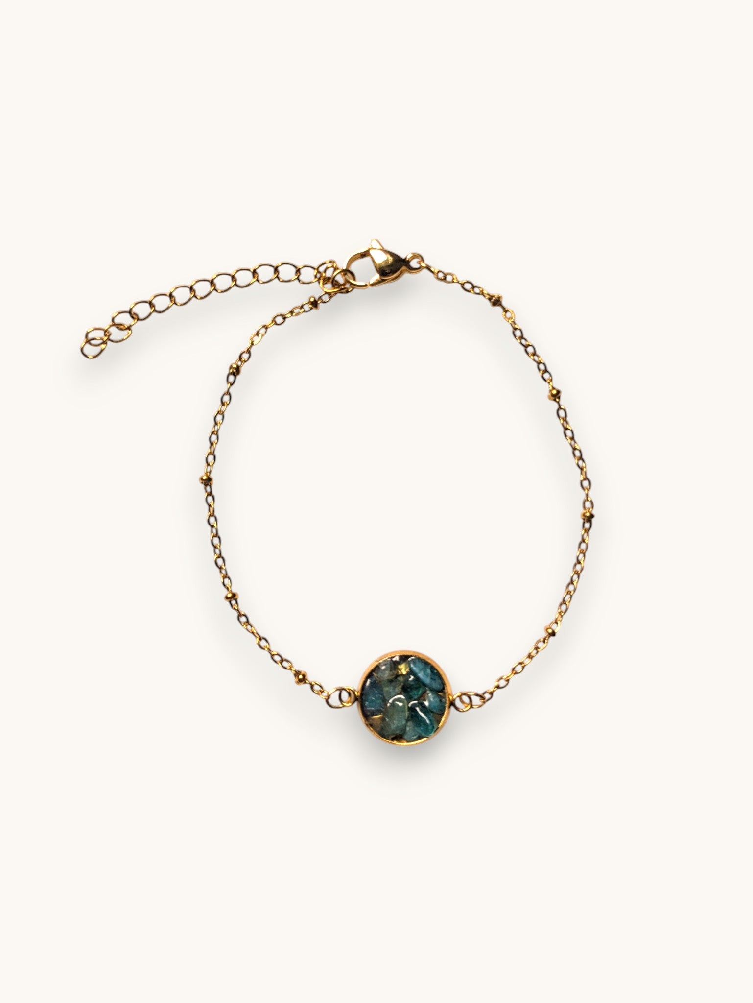 Citrinmagi armband i guld med en rund detalj fylld av skimrande blå stenar och justerbar kedja.
