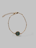 Citrinmagi armband i guld med en rund detalj fylld av skimrande blå stenar och justerbar kedja.