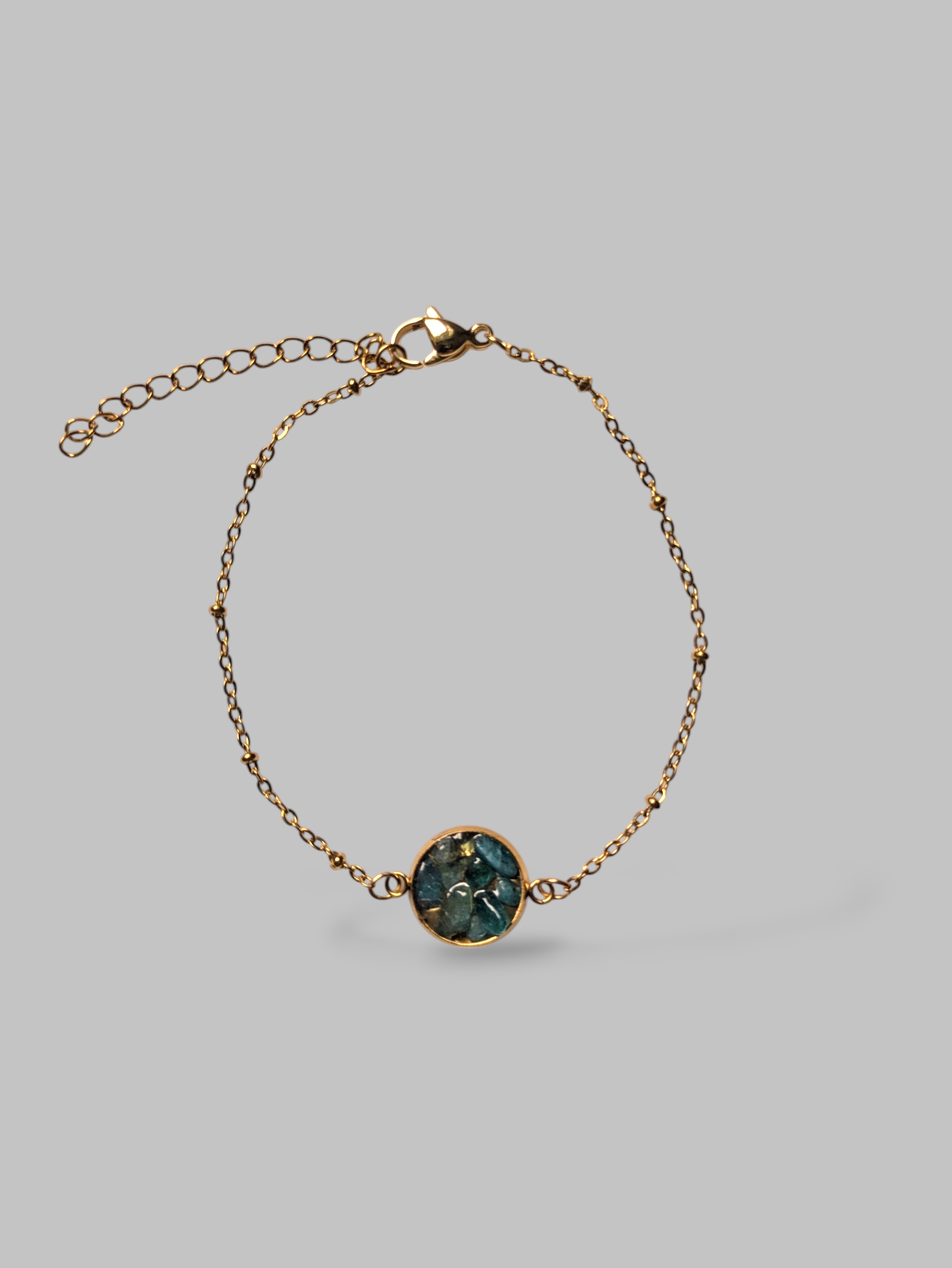 Citrinmagi armband i guld med en rund detalj fylld av skimrande blå stenar och justerbar kedja.