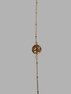 Citrinmagi armband i guld med fin kedja, små kuldetaljer och en rund bärnstensliknande sten i mitten.