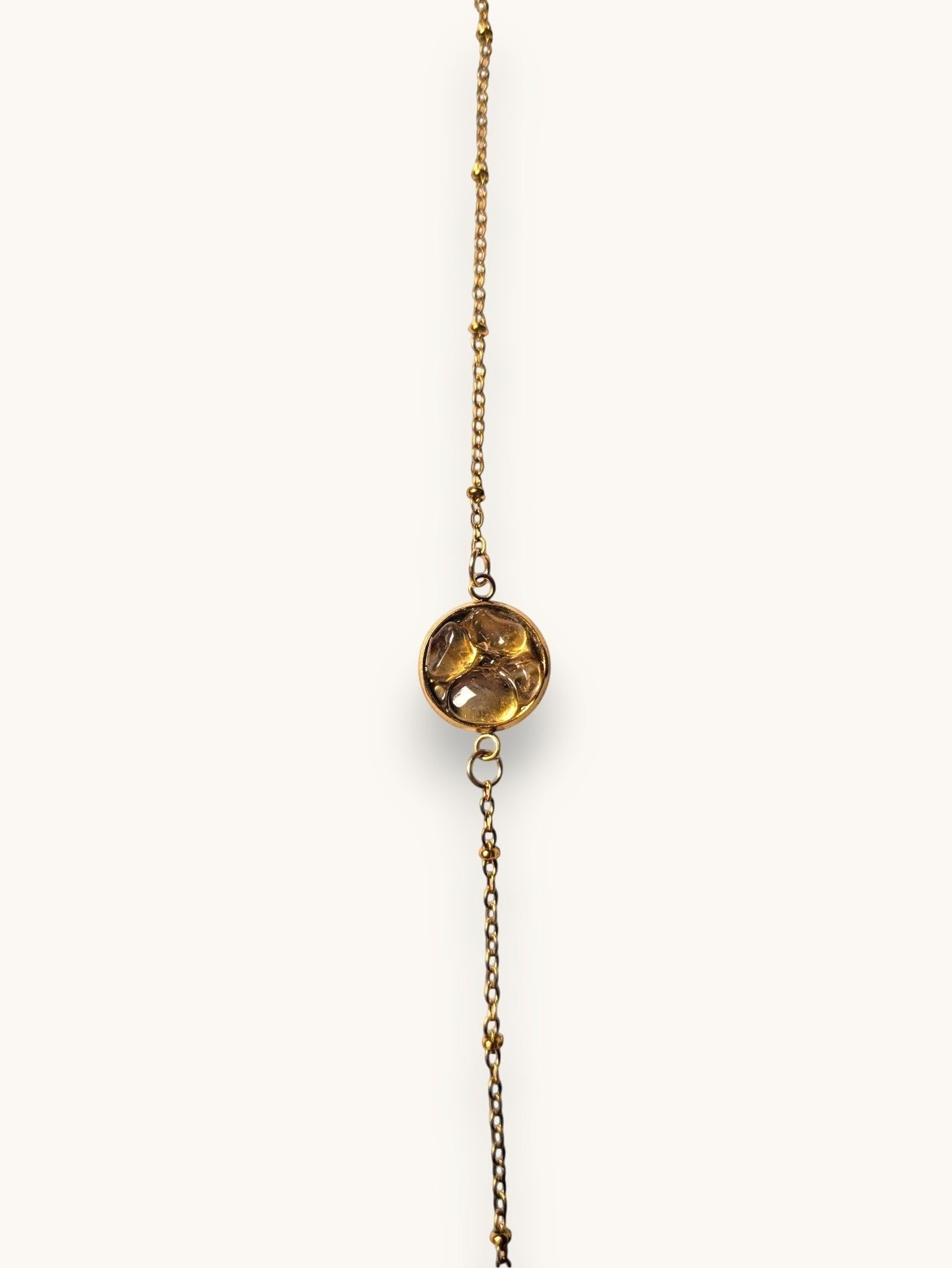 Citrinmagi armband i guld med fin kedja, små kuldetaljer och en rund bärnstensliknande sten i mitten.