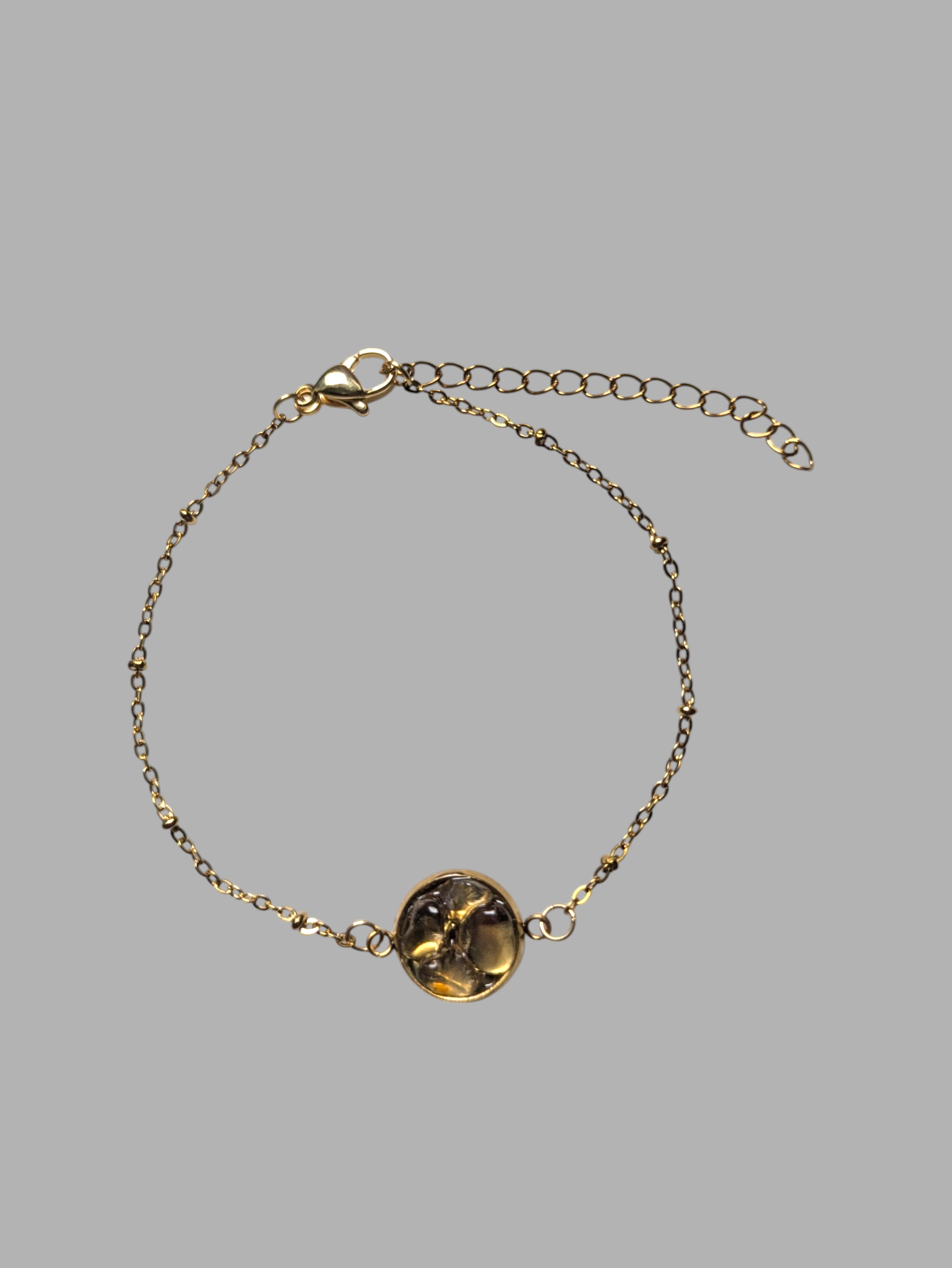 Citrinmagi armband i guldfärgad metall med en rund bärnstensliknande sten och dekorativa kulor på kedjan.