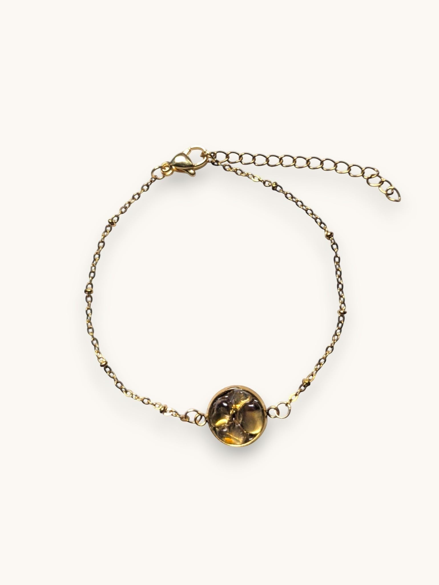 Citrinmagi armband i guldfärgad metall med en rund bärnstensliknande sten och dekorativa kulor på kedjan.