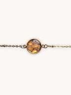 Citrinmagi guldtonat armband med rund detalj fylld av slipade stenar i varma jordnära nyanser på marmorbakgrund