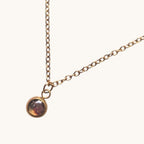 Citrinmagi halsband i antik mässing med en minimalistisk rund stenberlock på en nätt kedja mot en vit marmoryta.
