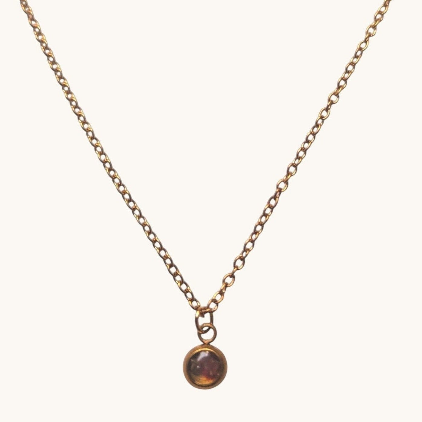 Citrinmagi halsband med nätt kedja och rund sten i antik mässingsfinish mot en vit marmorbakgrund.