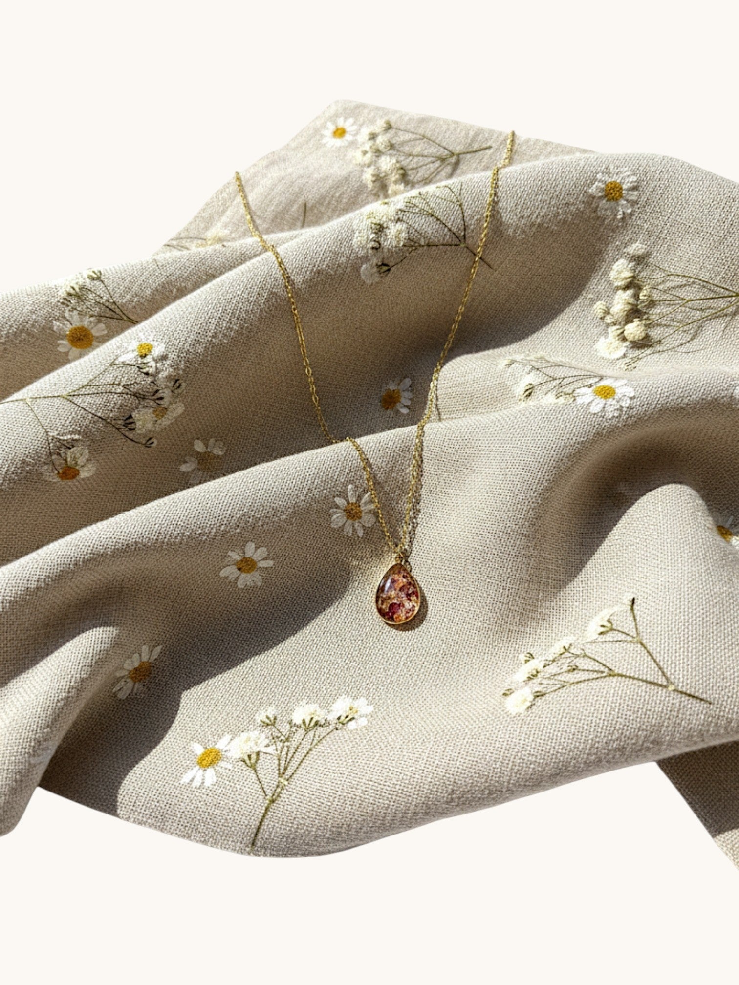 Citrinmagi halsband med droppformad granat i 18k guldpläterat stål, placerat på ett blommigt tyg.