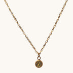 Nayuga Jewels halsband i antik guldton med en liten rund olivgrön sten på en klassisk länk-kedja.