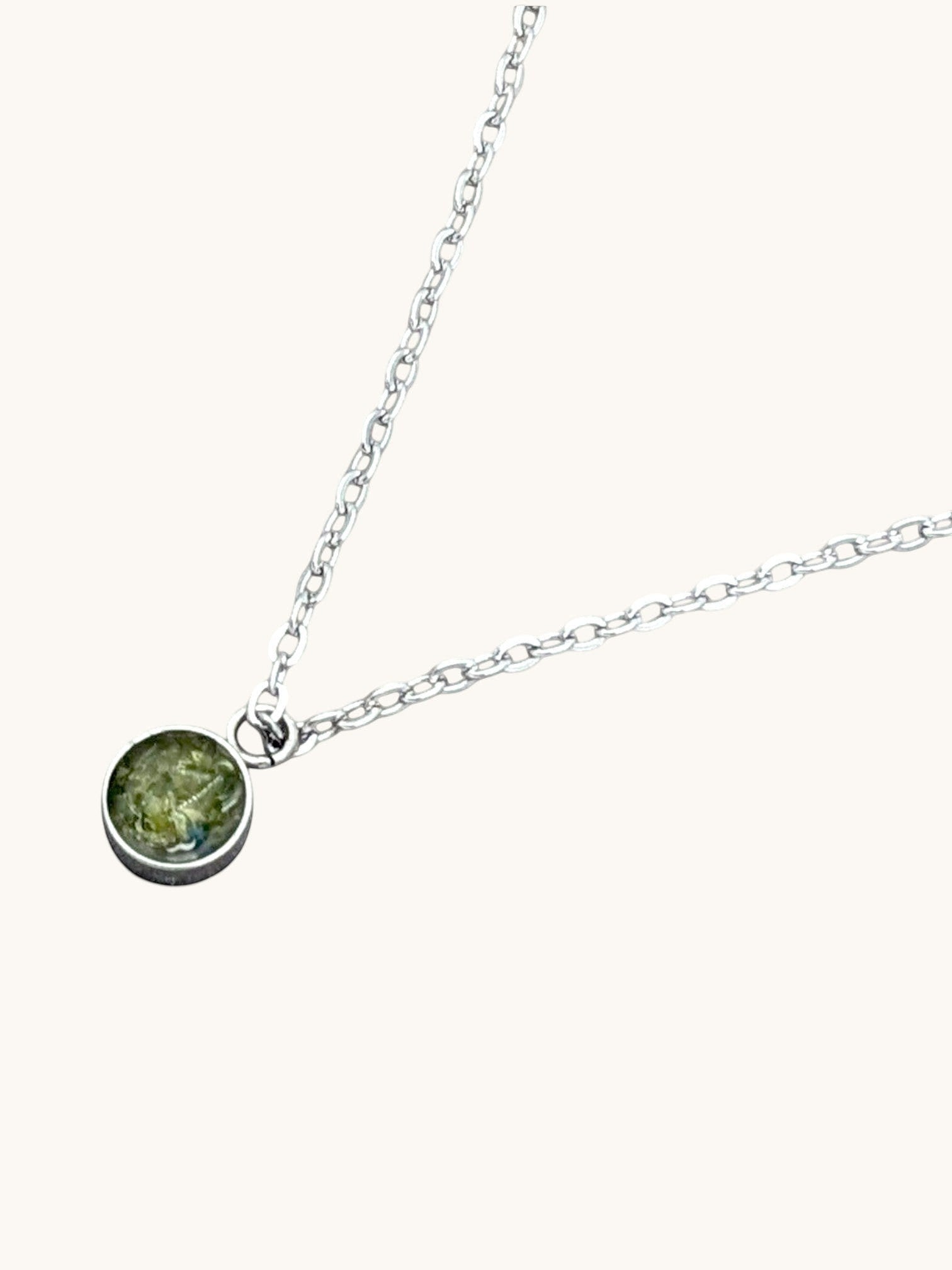 Nayuga Jewels halsband med rund berlock och äkta grön peridot infattad i silverpläterat rostfritt stål.
