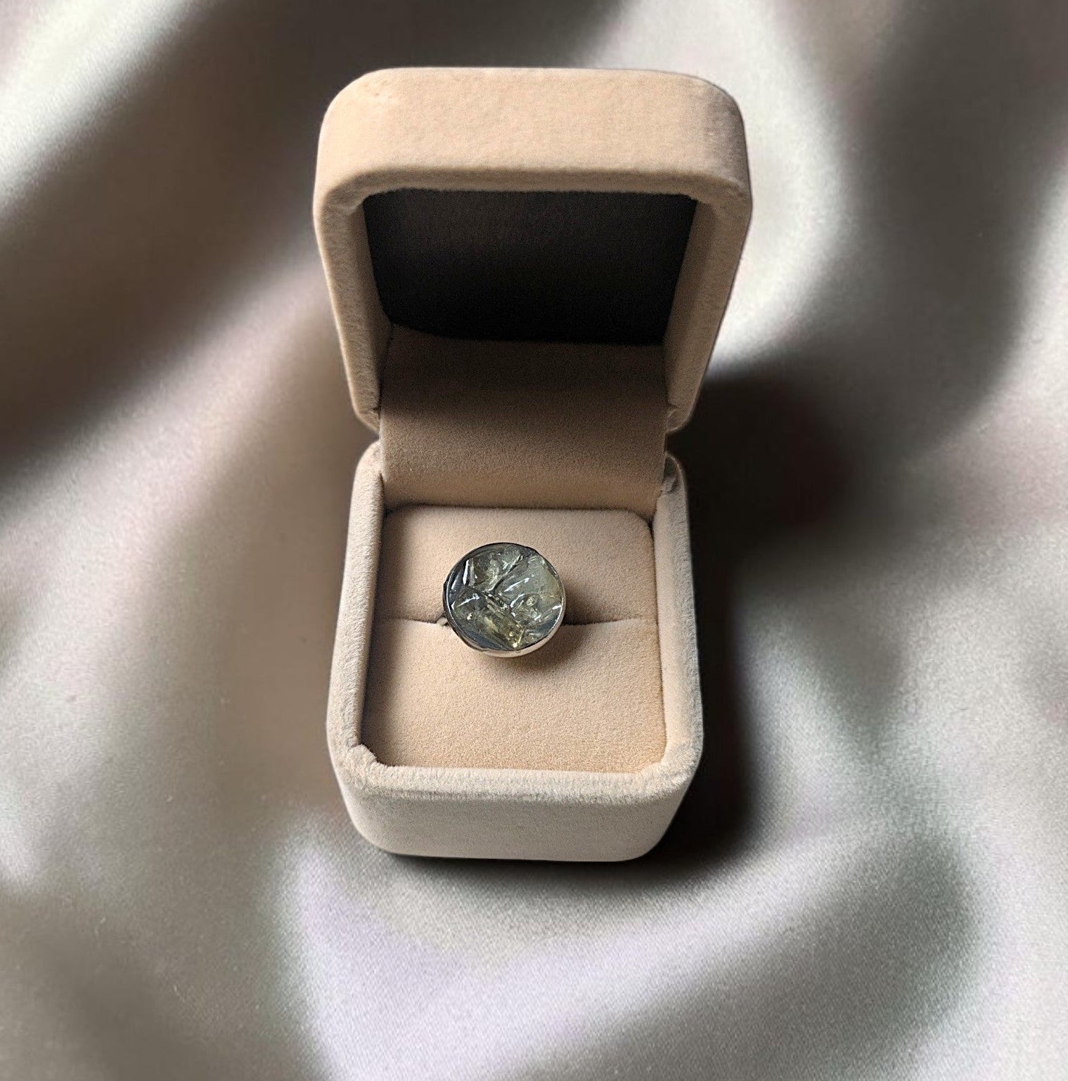 Citrinmagi handgjord ring med rund grön texturerad sten i silverfärgad infattning, presenterad i en beige ask.