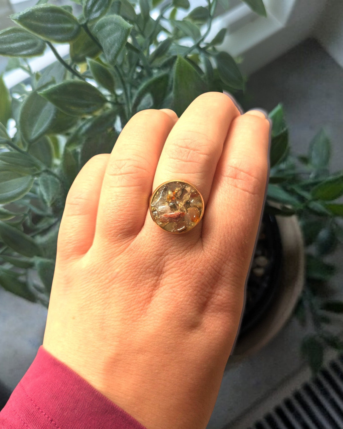 Citrinmagi handgjord guldring med rund infattning fylld av glittrande stenar och organiska detaljer på ett finger.
