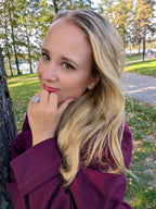 Citrinmagi hjärtformad silverring med texturerad yta buren av en kvinna i en parkmiljö.