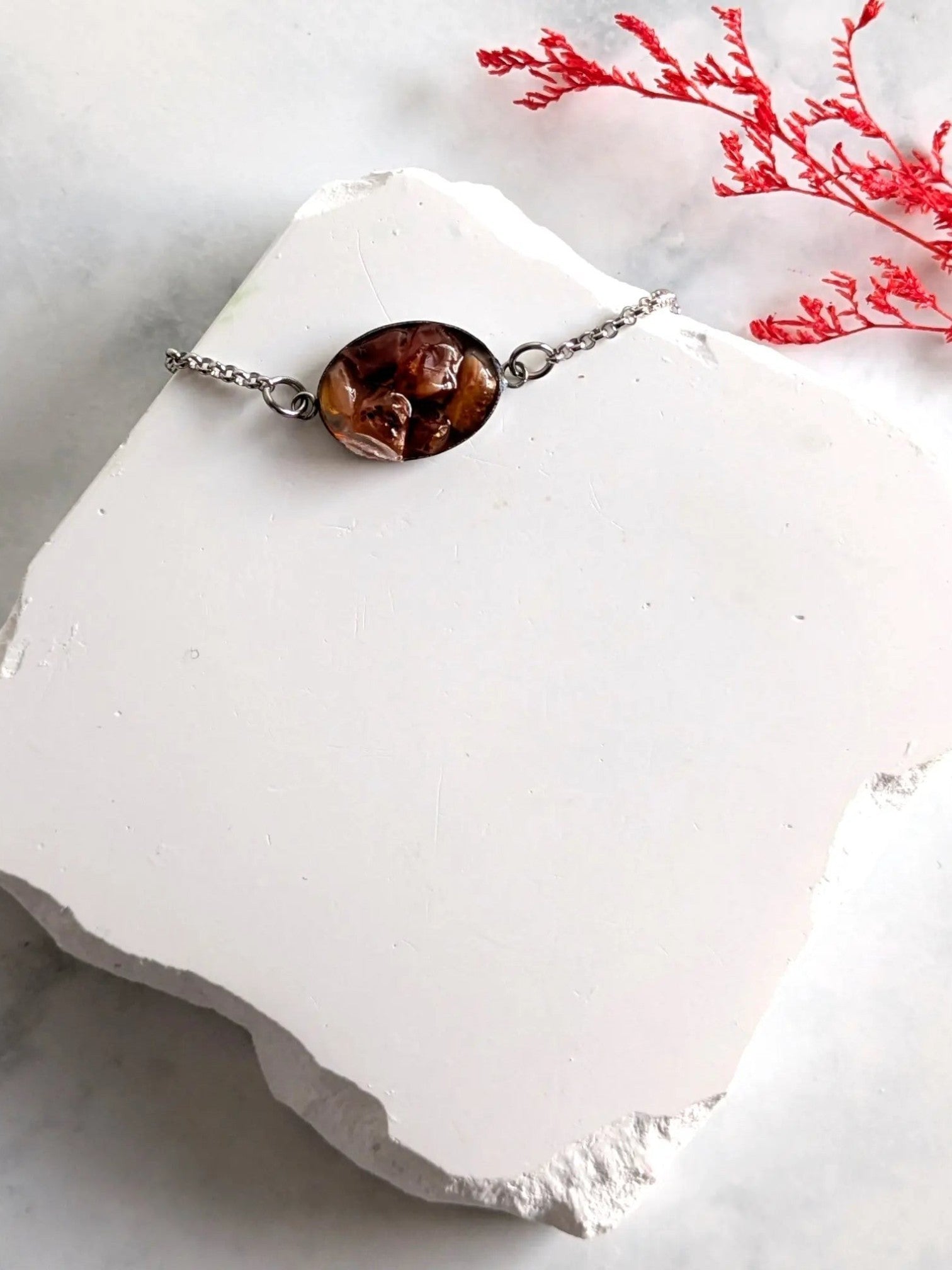 Citrinmagi armband med oval äkta karneol i silverfärgad infattning och kedja på en vit stenplatta
