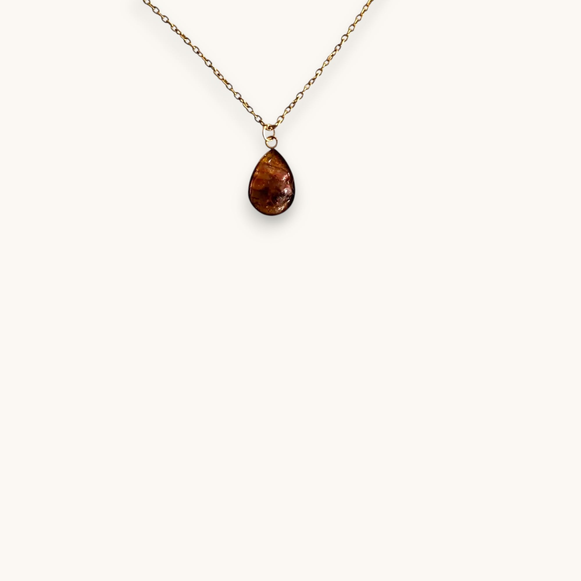 Citrinmagi handgjort halsband med droppformad karneol i 14k guldpläterad ram på vit stenplatta.