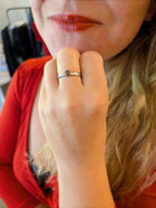 Citrinmagi minimalistisk silverring med en liten orange-röd karneolkristall buren på ett finger.