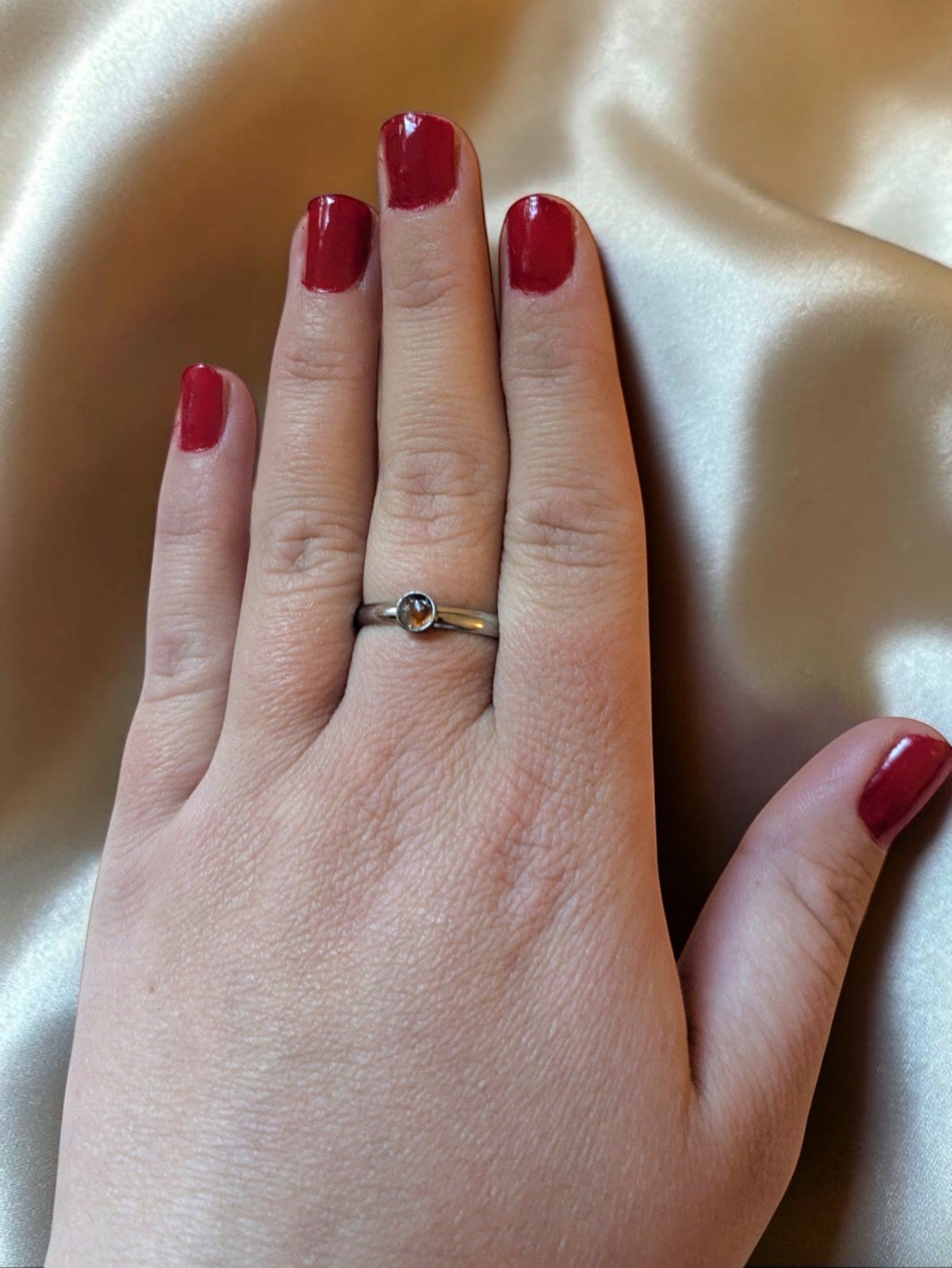 Citrinmagi minimalistisk ring i silver med en liten orange-röd karneolkristall buren på ett finger