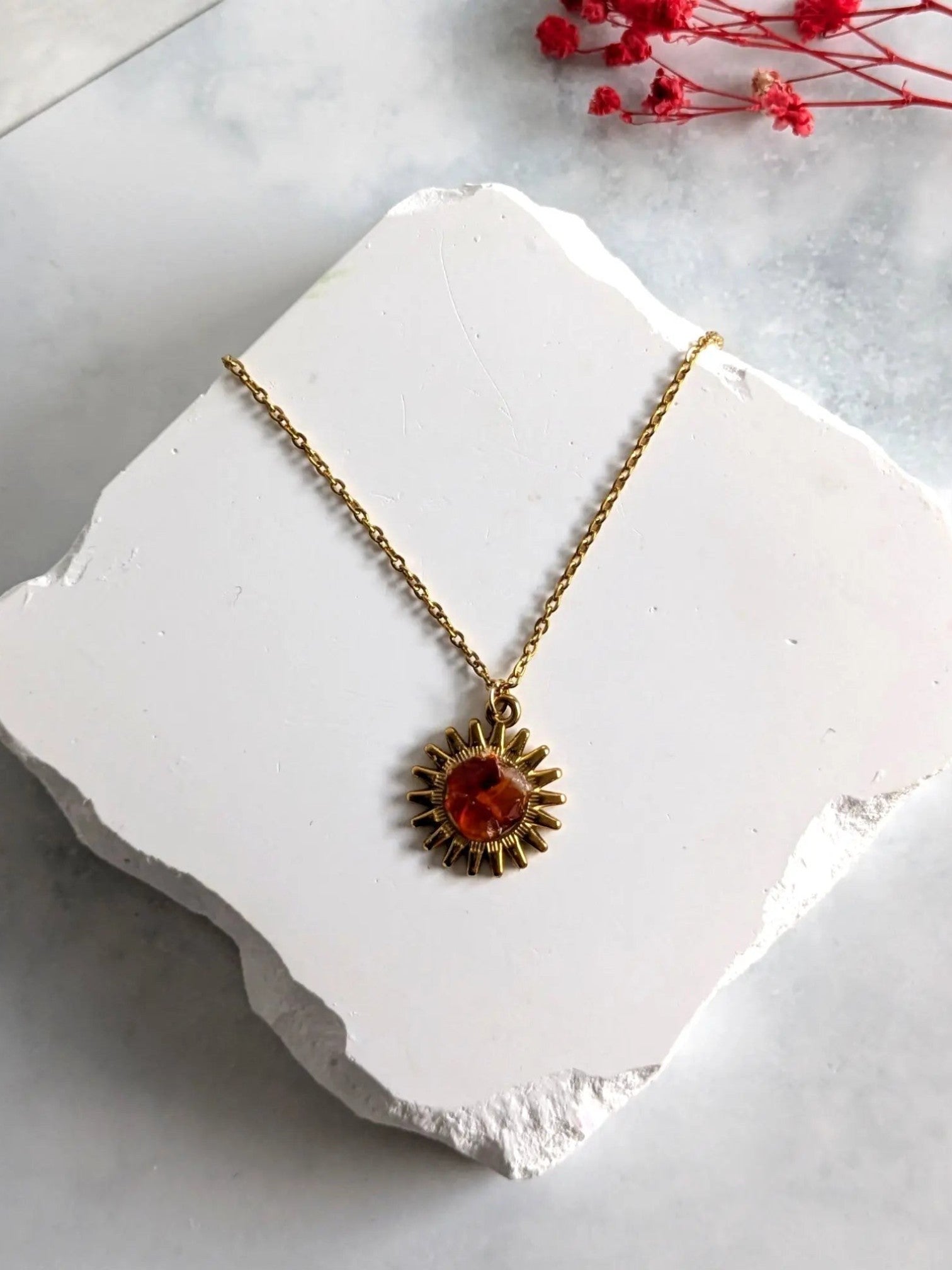 Nayuga Jewels halsband med karneol i en guldpläterad solinfattning, presenterat på en vit stenplatta.