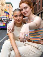 Citrinmagi Pride-ring i silver med hjärtformade flerfärgade kristaller buren av en kvinna under en Pride-parad.