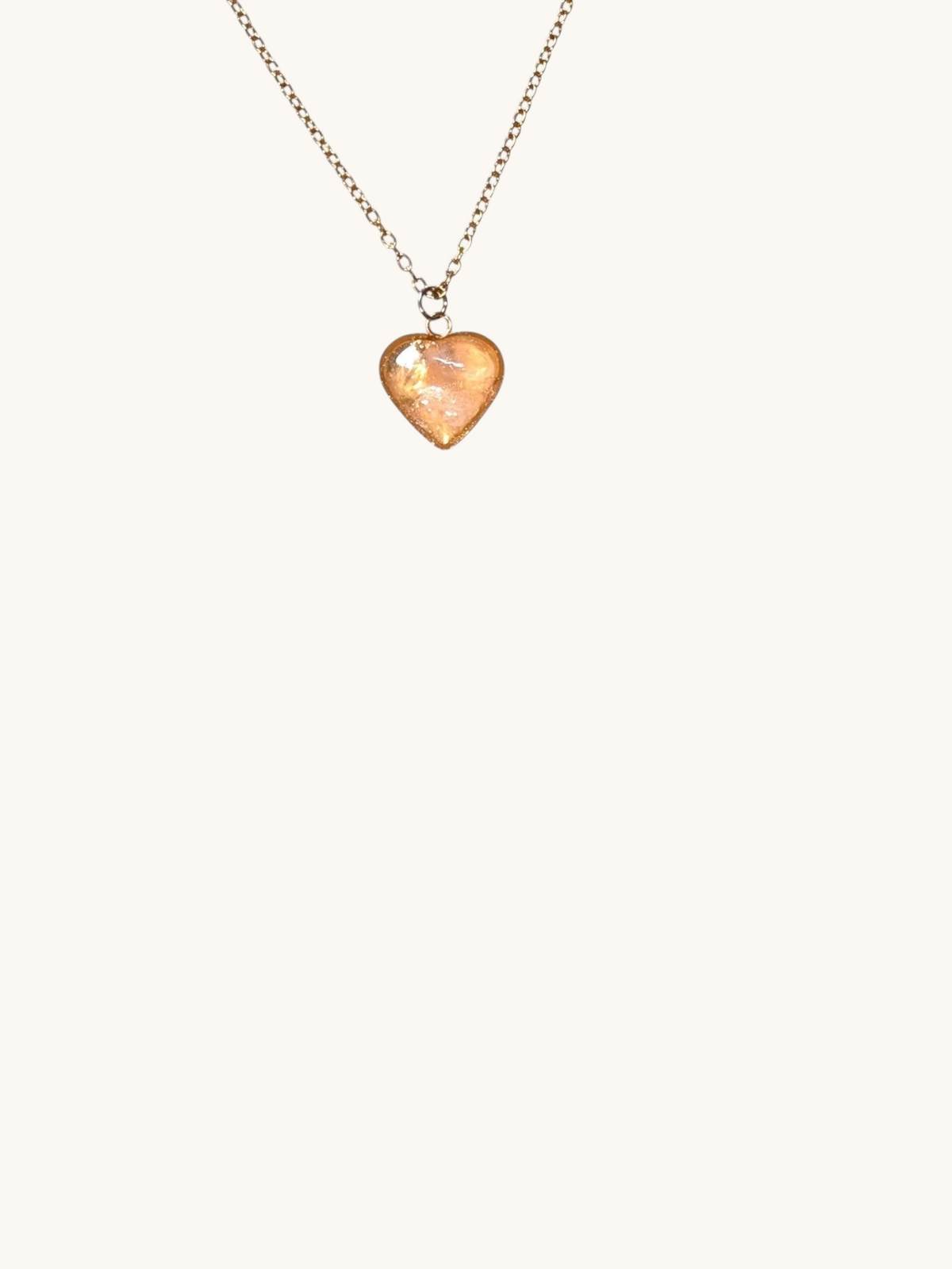 Citrinmagi halsband med hjärtformat hänge i rosenkvarts och 18k guldpläterad kedja på en vit marmoryta.