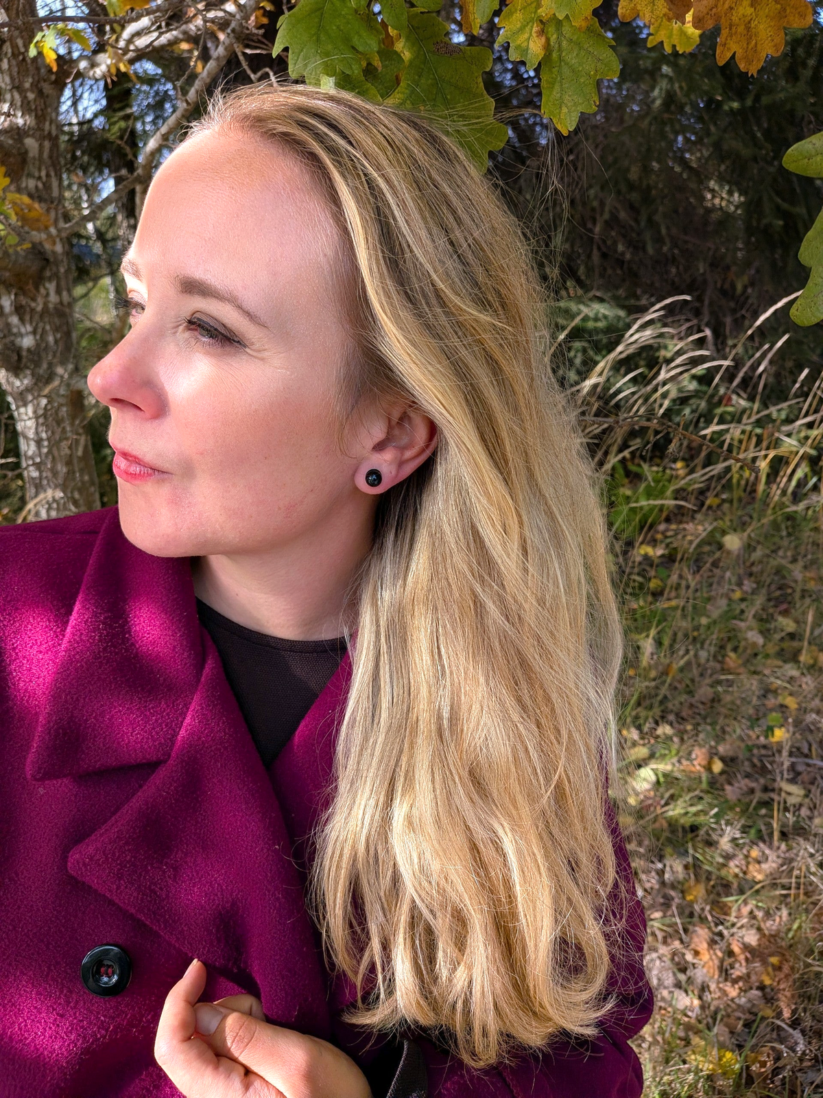 Citrinmagi minimalistiska runda svarta örhängen burna av kvinna i lila kappa utomhus i höstmiljö