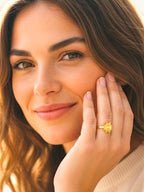 Citrinmagi Solstråle ring i guldpläterad design med solmotiv buren av en kvinna för en elegant och varm look.