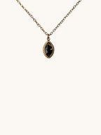 Citrinmagi halsband med oval svart obsidian infattad i guldpläterat rostfritt stål på en tunn guldkedja.