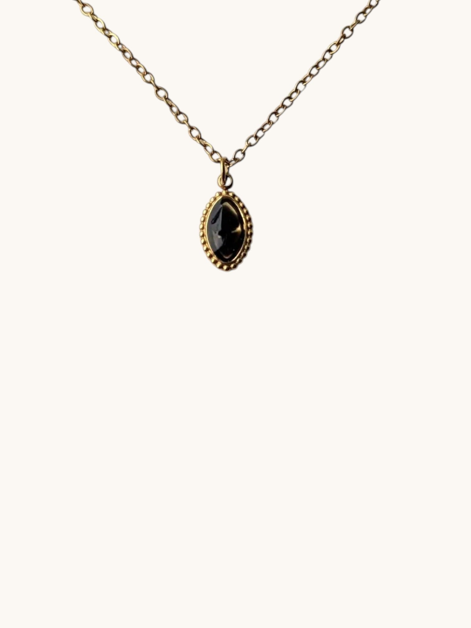 Citrinmagi halsband med oval svart obsidian infattad i guldpläterat rostfritt stål på en tunn guldkedja.