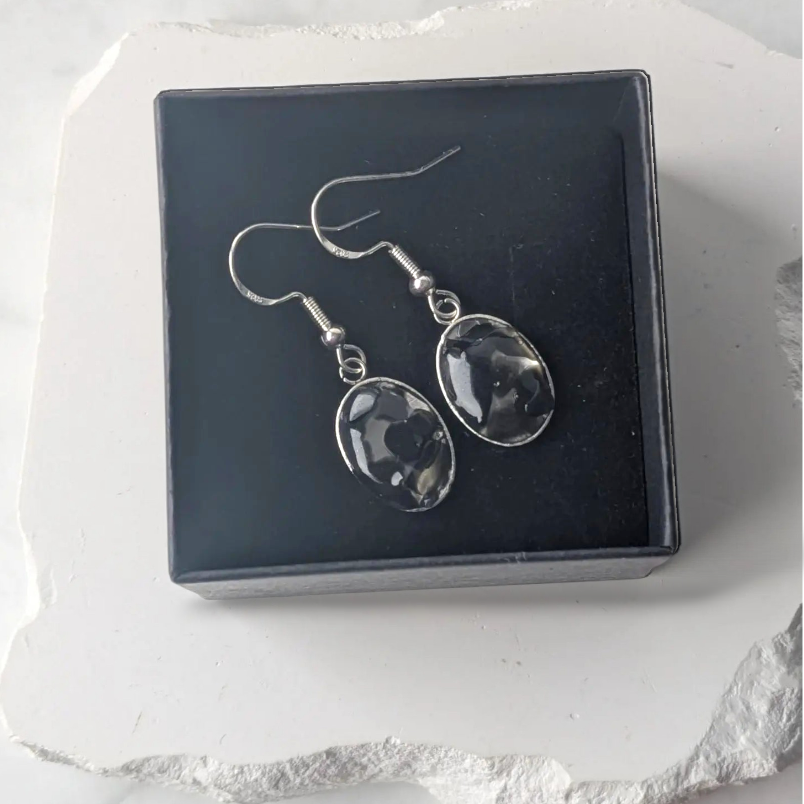 Citrinmagi örhängen med svart obsidian i silverpläterad infattning, presenterade i en elegant smyckesask.