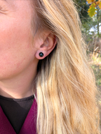 Citrinmagi minimalistiska runda svarta örhängen med glansig finish burna av en kvinna med blont hår utomhus